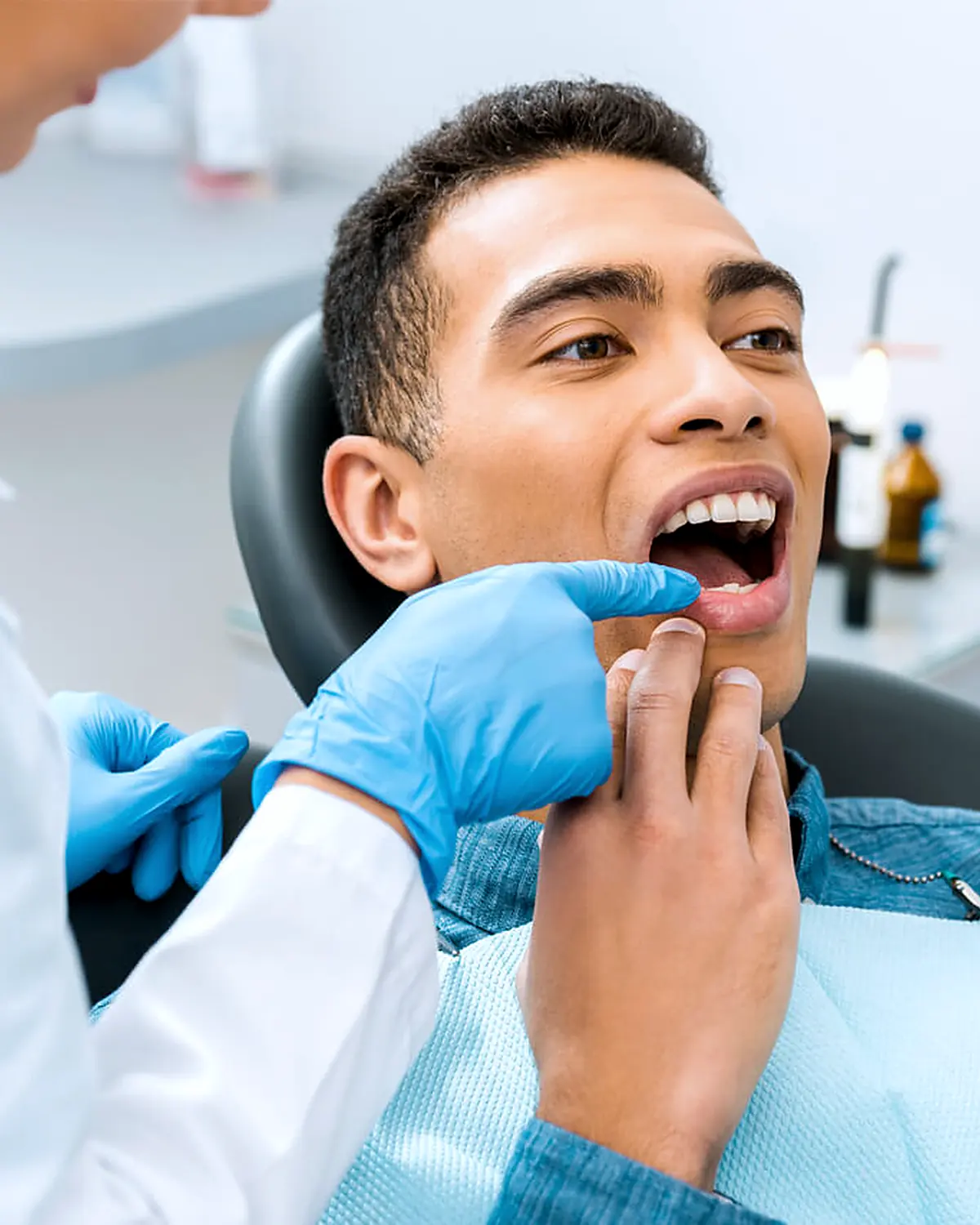 A dentist showing a patient their teeth in a hand mirror during a consultation
